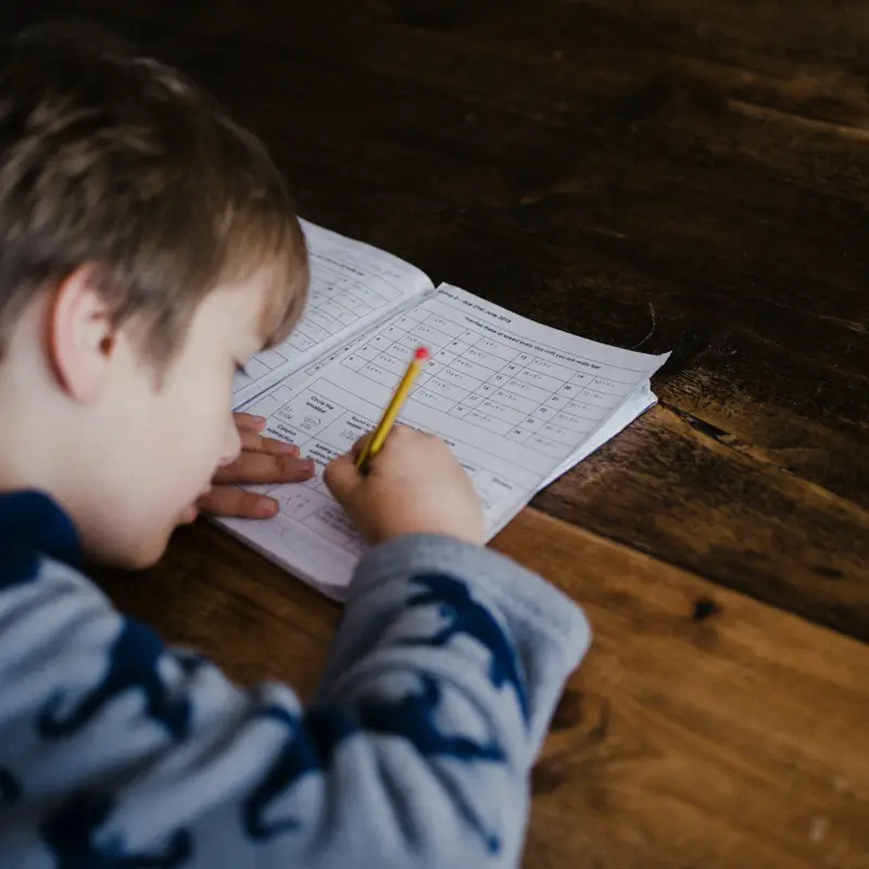 enfant concentré faisant ses devoirs à l'école sur une feuille d'exercices