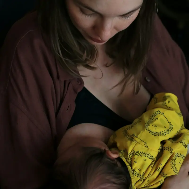 femme allaitant son bébé avec un tissu jaune à motifs