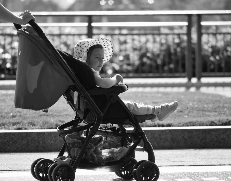 Adorable baby in a sun hat enjoys a stroll in a stroller, black and white urban setting.