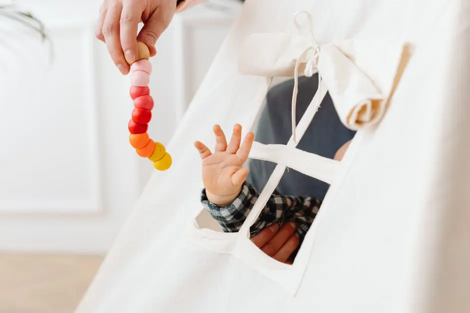 A baby reaches for a colorful toy through a teepee tent window, symbolizing curiosity and play.