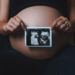 a pregnant woman holding a camera in her hands