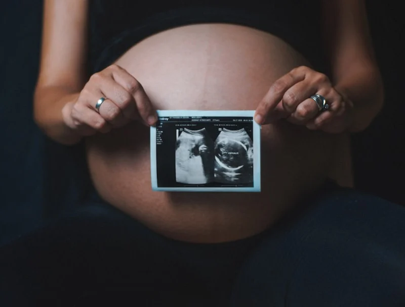 a pregnant woman holding a camera in her hands