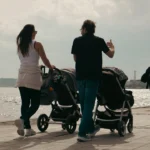 Parents stroll with double strollers by the water