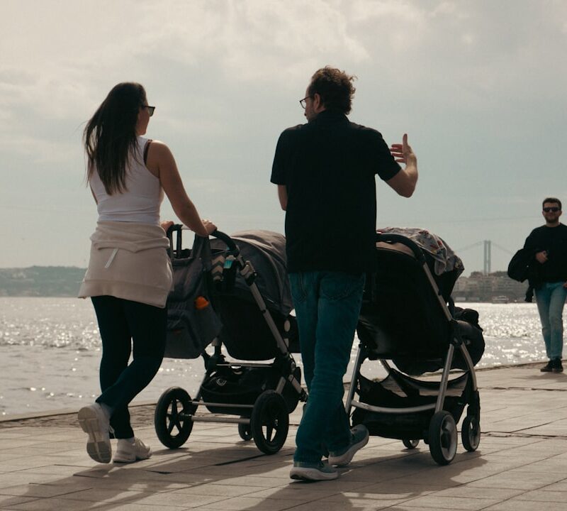 Parents stroll with double strollers by the water