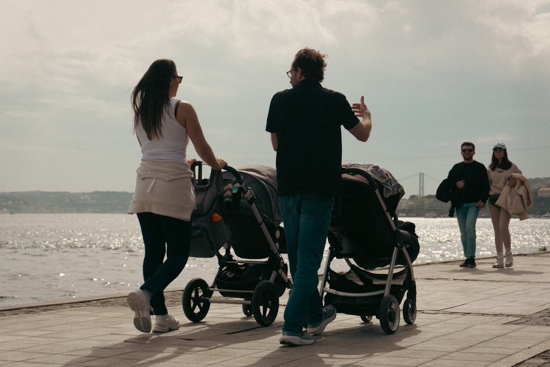 Parents stroll with double strollers by the water