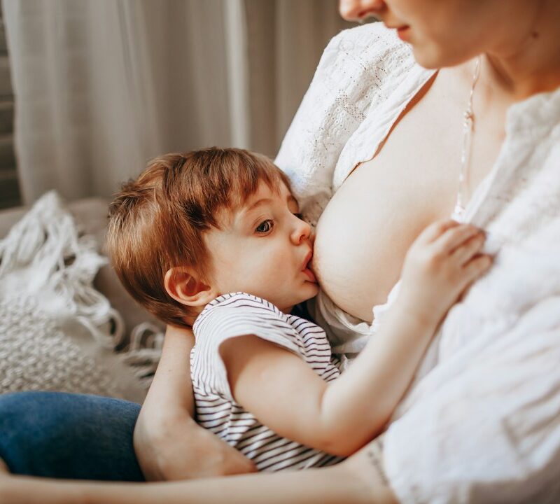 woman in white tank top carrying baby in black and white stripe onesie